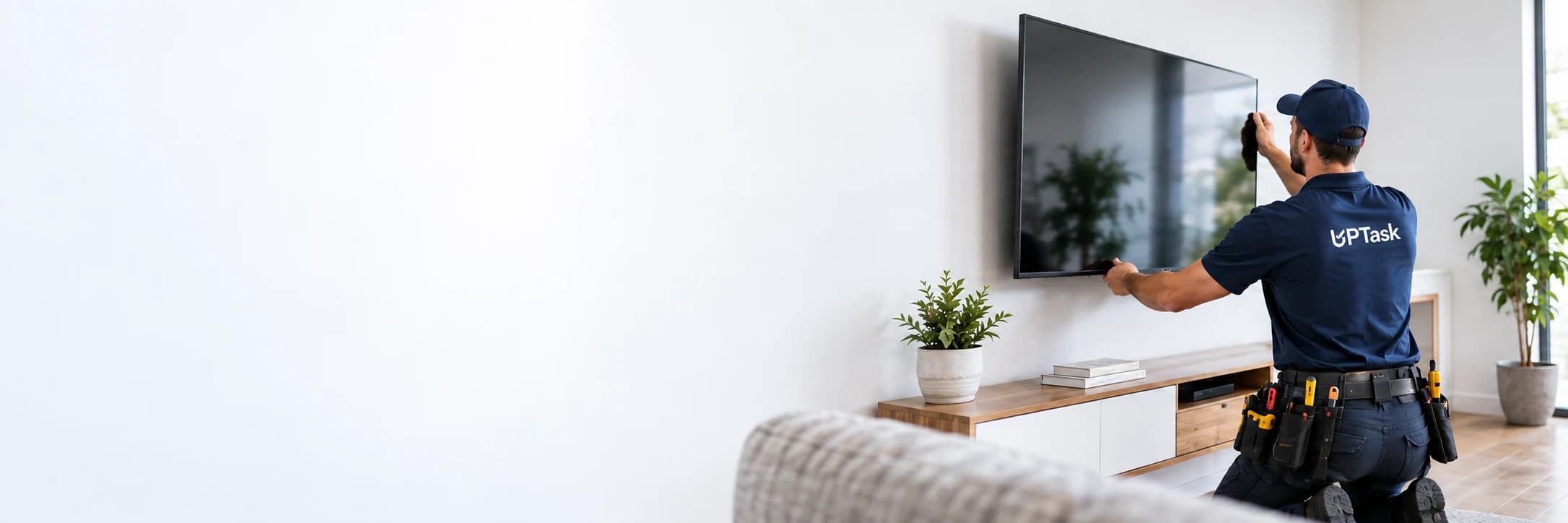 UPTask professional mounting a television in a bright living room